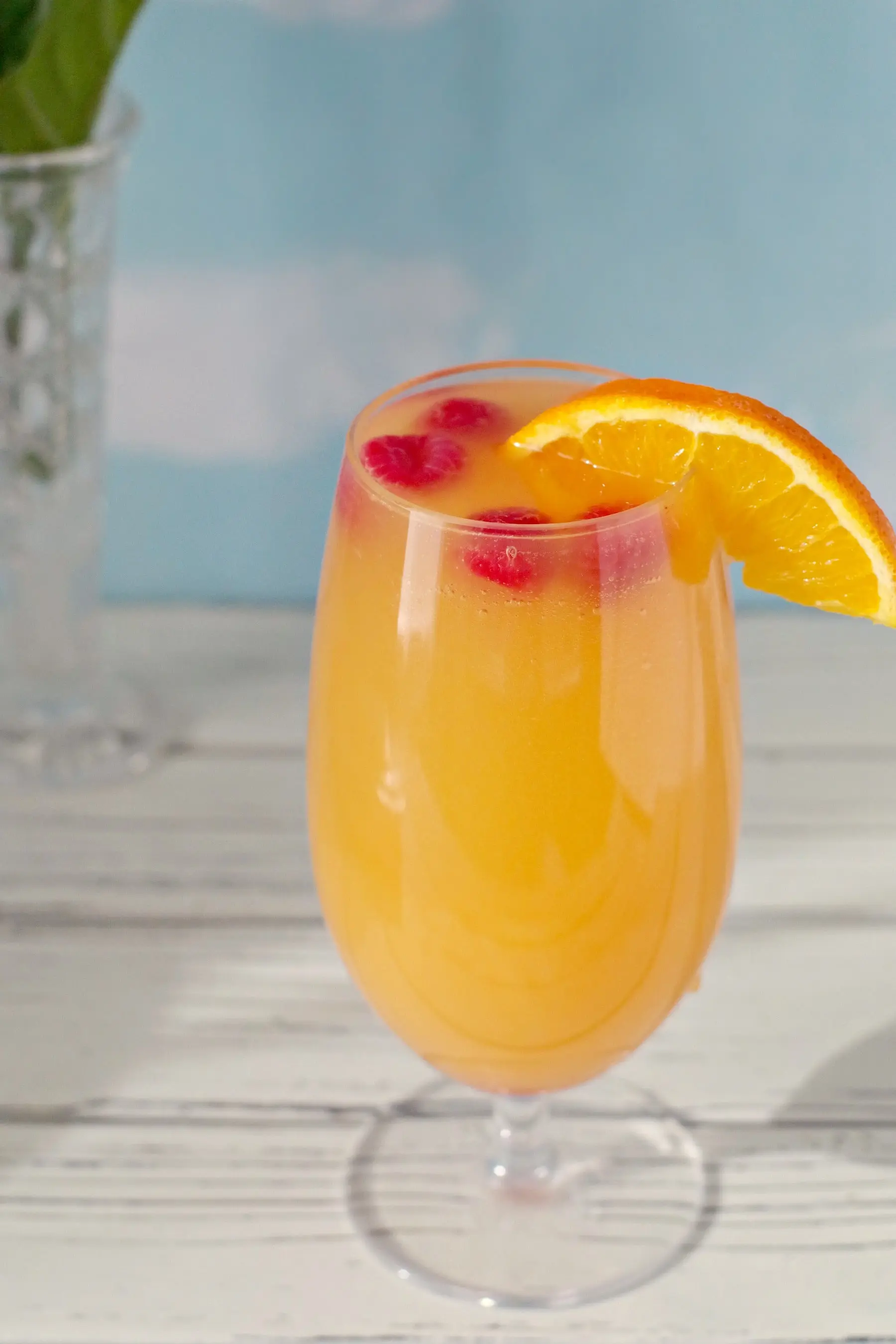 mimosa drink with raspberries and orange garnish