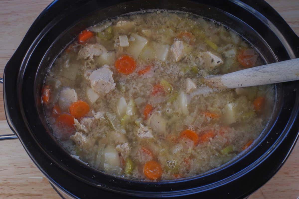 roux being stirred into slow cooker chicken stew