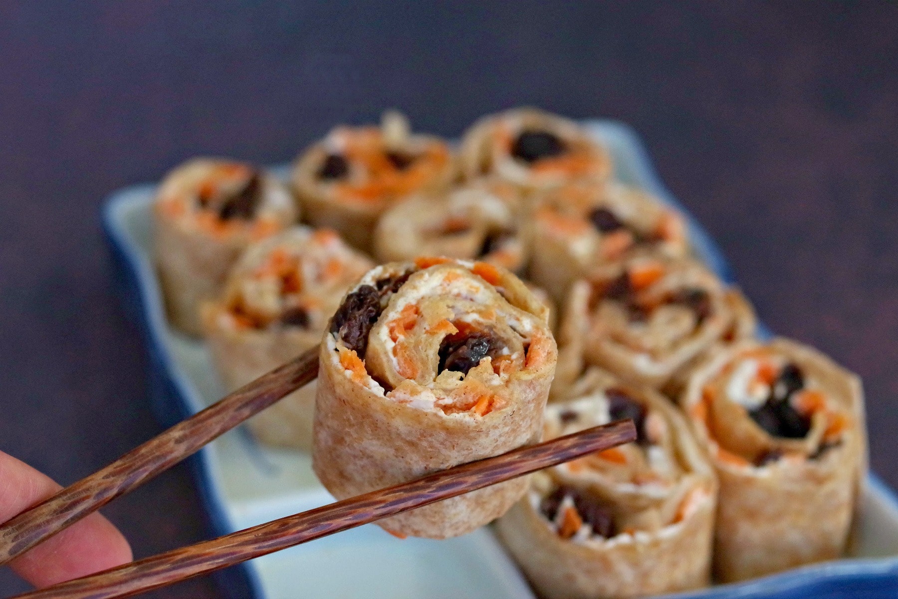 raisin sushi being held up with chopsticks