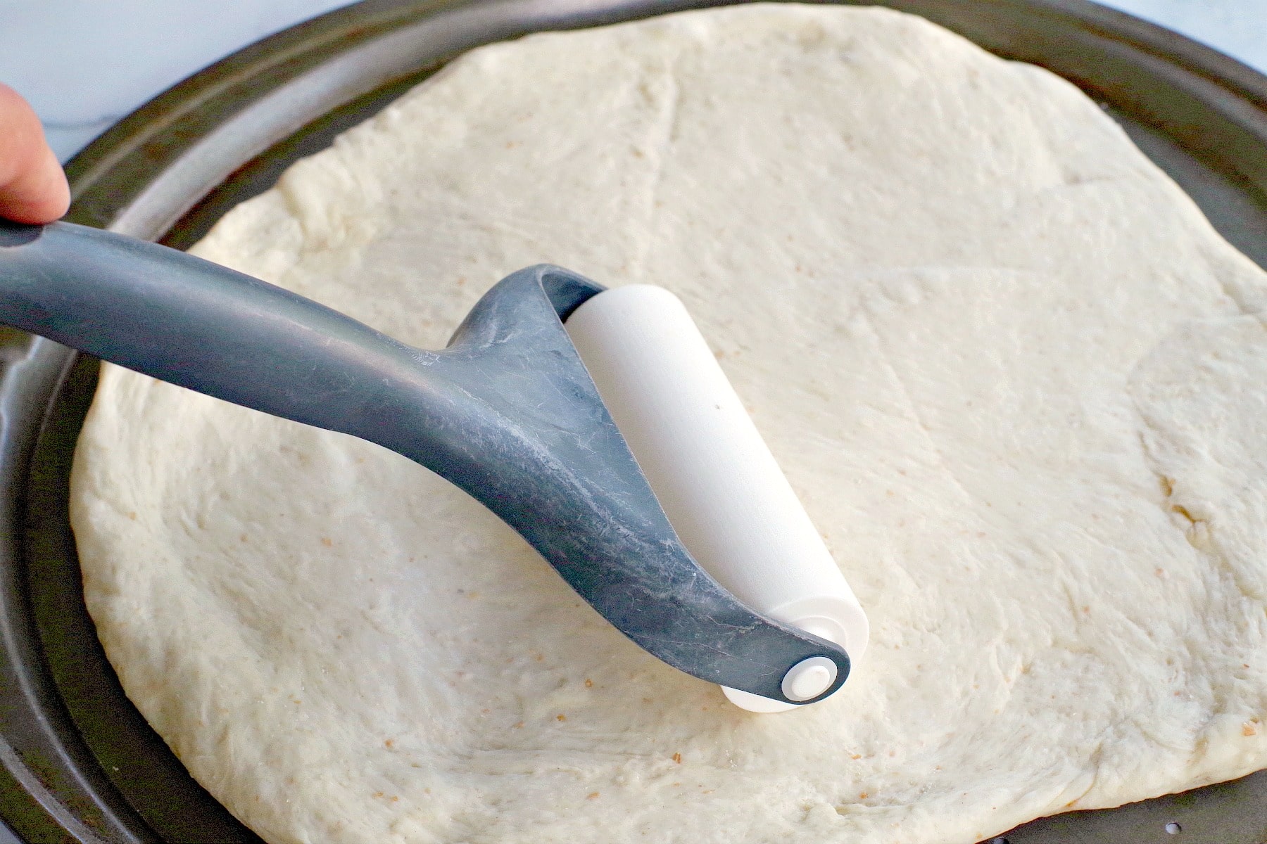 pizza dough being rolled out on pizza pan