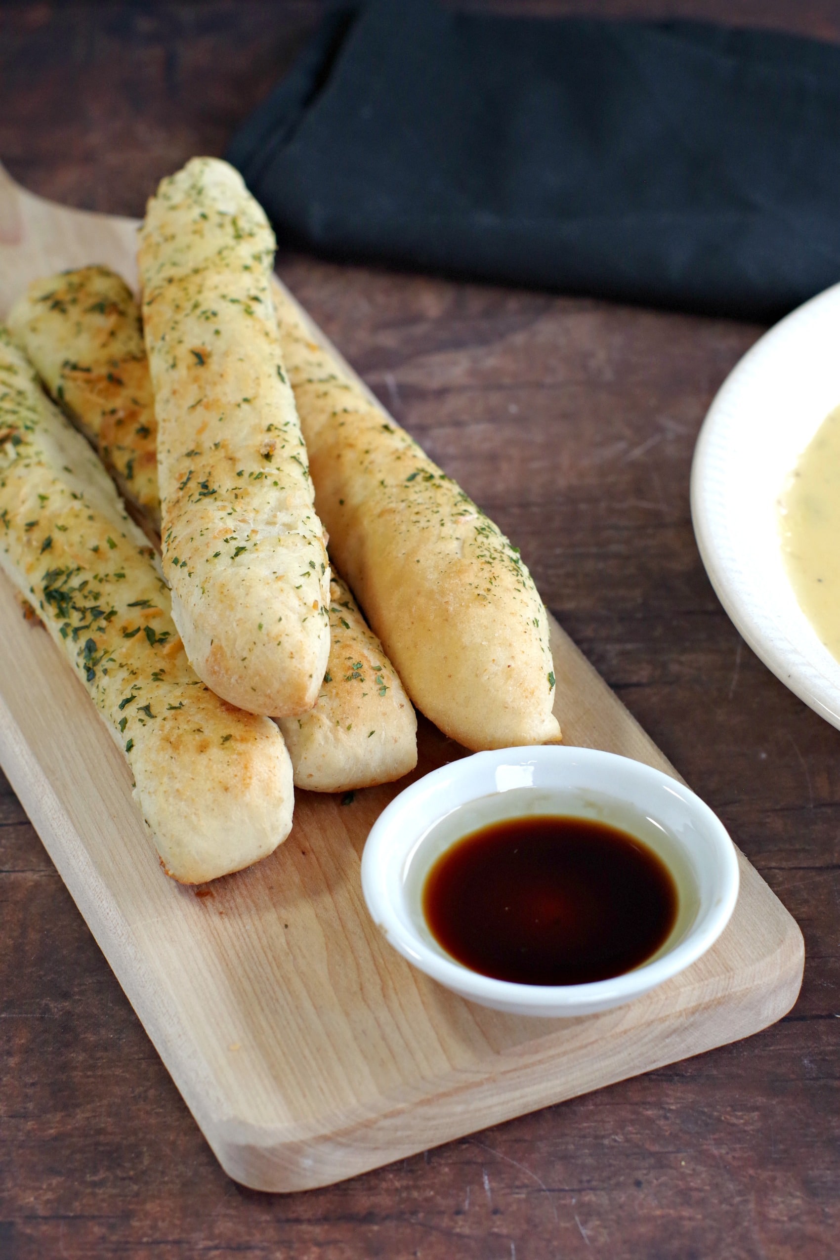 bread machine Italian breadsticks on a bread board with balsamic vinegar and oil dip