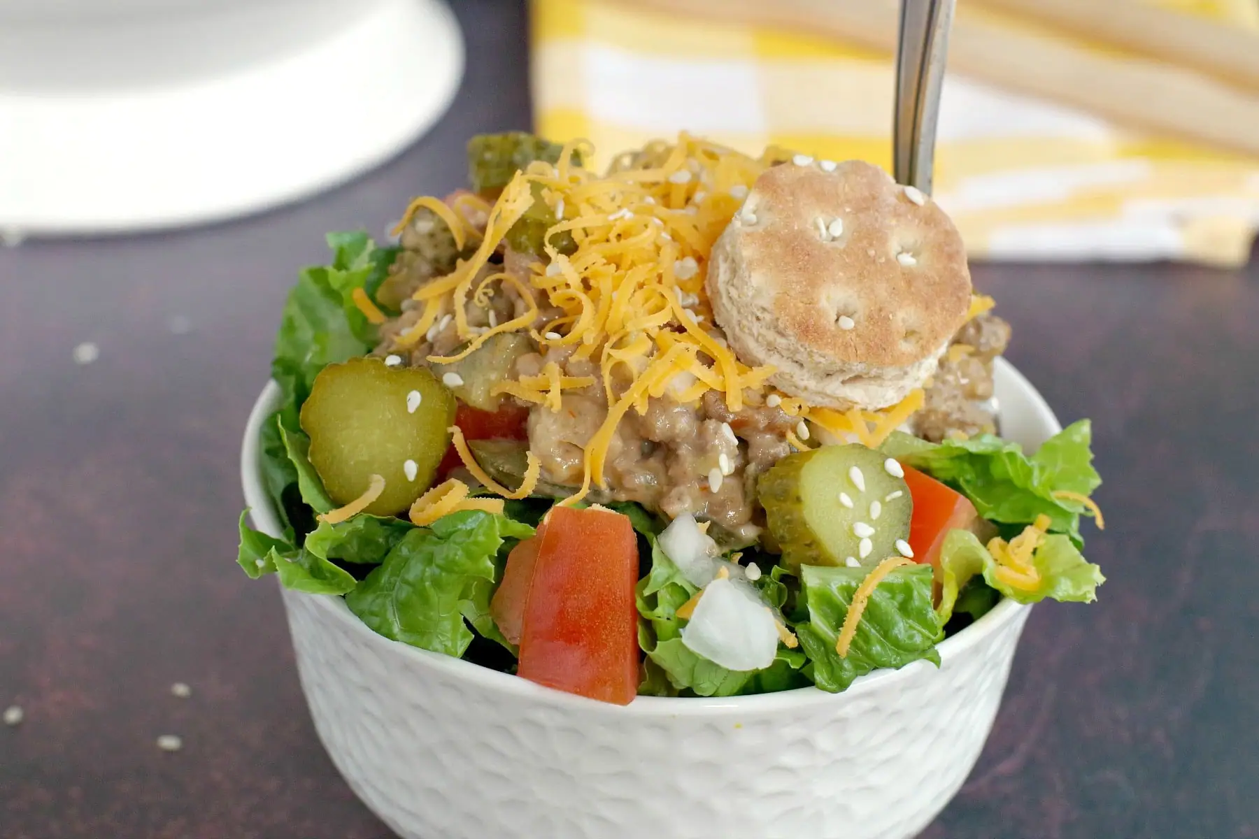 big mac salad in small white bowl, with yellow and white checkered tea towel in background