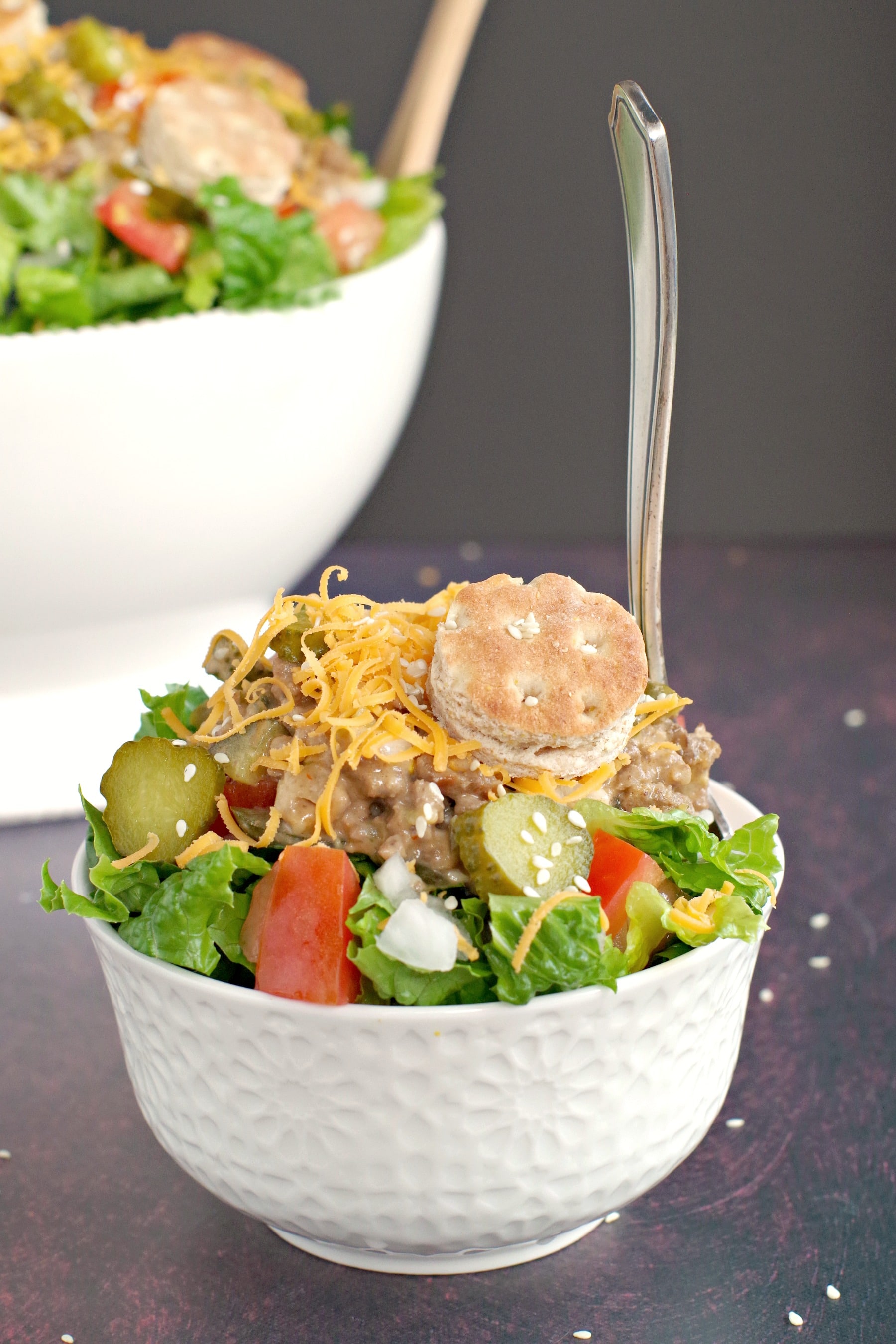 big mac salad in small white bowl with fork in it and large white salad bowl in background