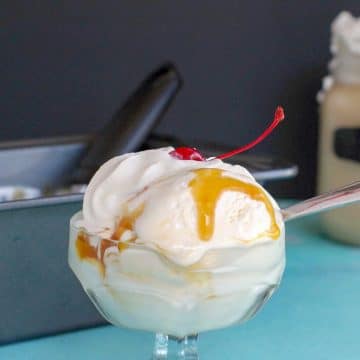 butterbeer ice cream in glass dessert dish, with loaf pan full of butterbeer in the background and a butterbeer drink in glass jar