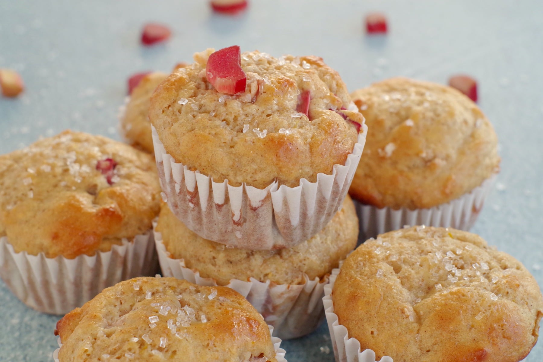 rhubarb muffin stacked on top of other rhubarb muffins with a piece of rhubarb on top