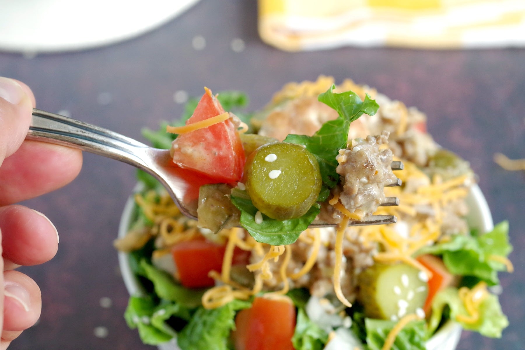 big mac salad being held up on a fork with bowl below