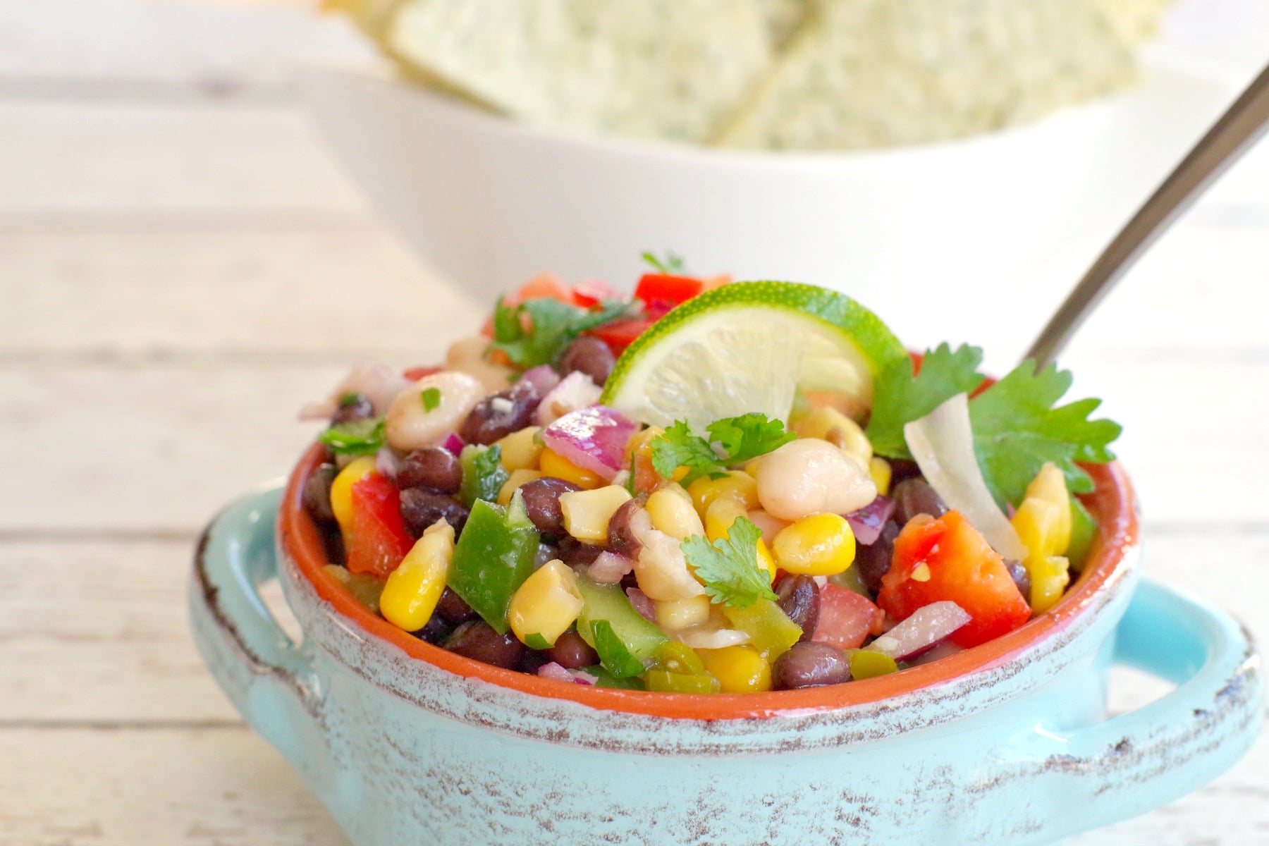 cowboy caviar in a blue bowl with tortilla chips in the background