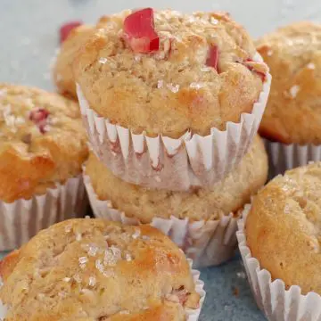 rhubarb muffin stacked on top of other rhubarb muffins with a piece of rhubarb on top