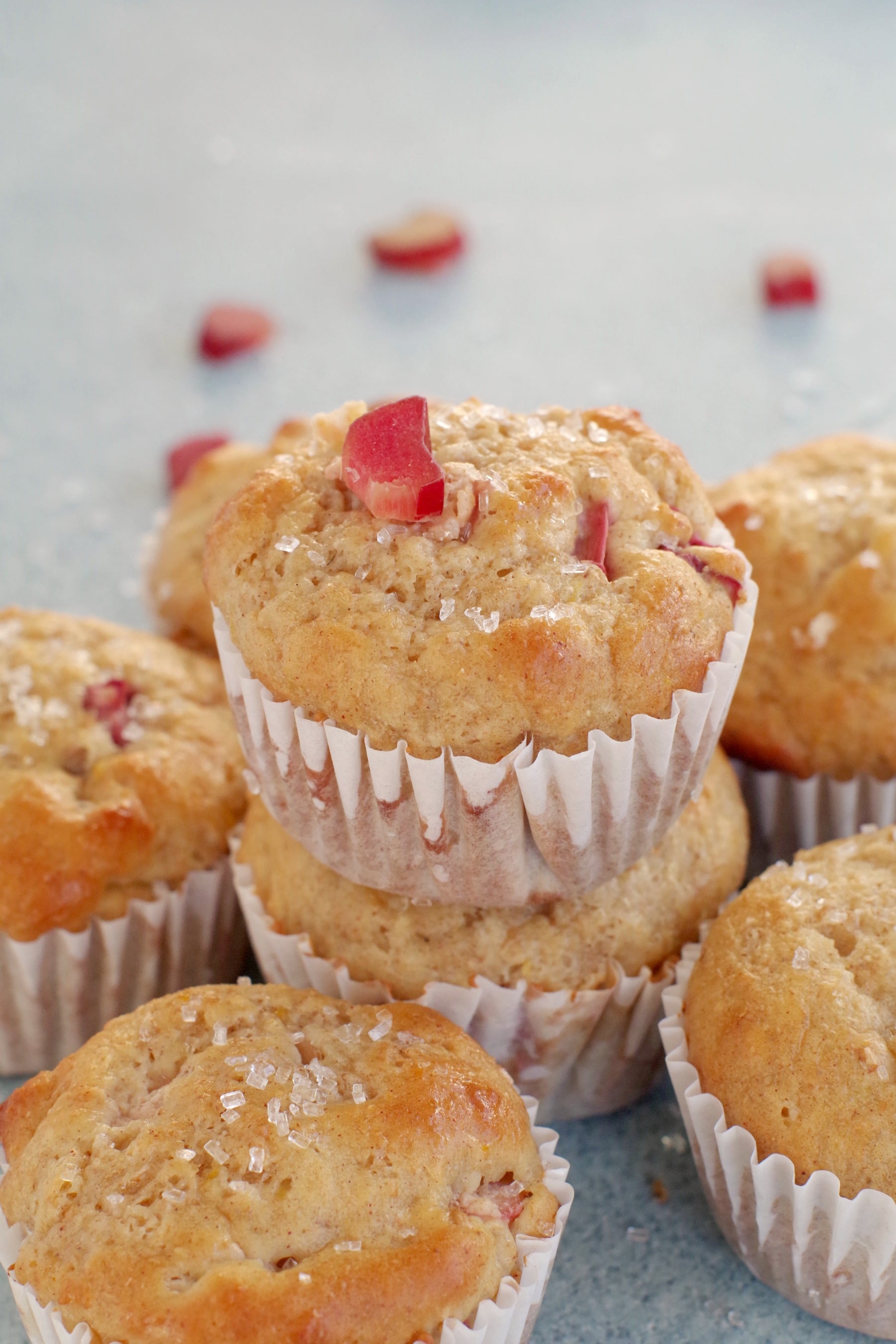 rhubarb muffin stacked on top of other rhubarb muffins with a piece of rhubarb on top