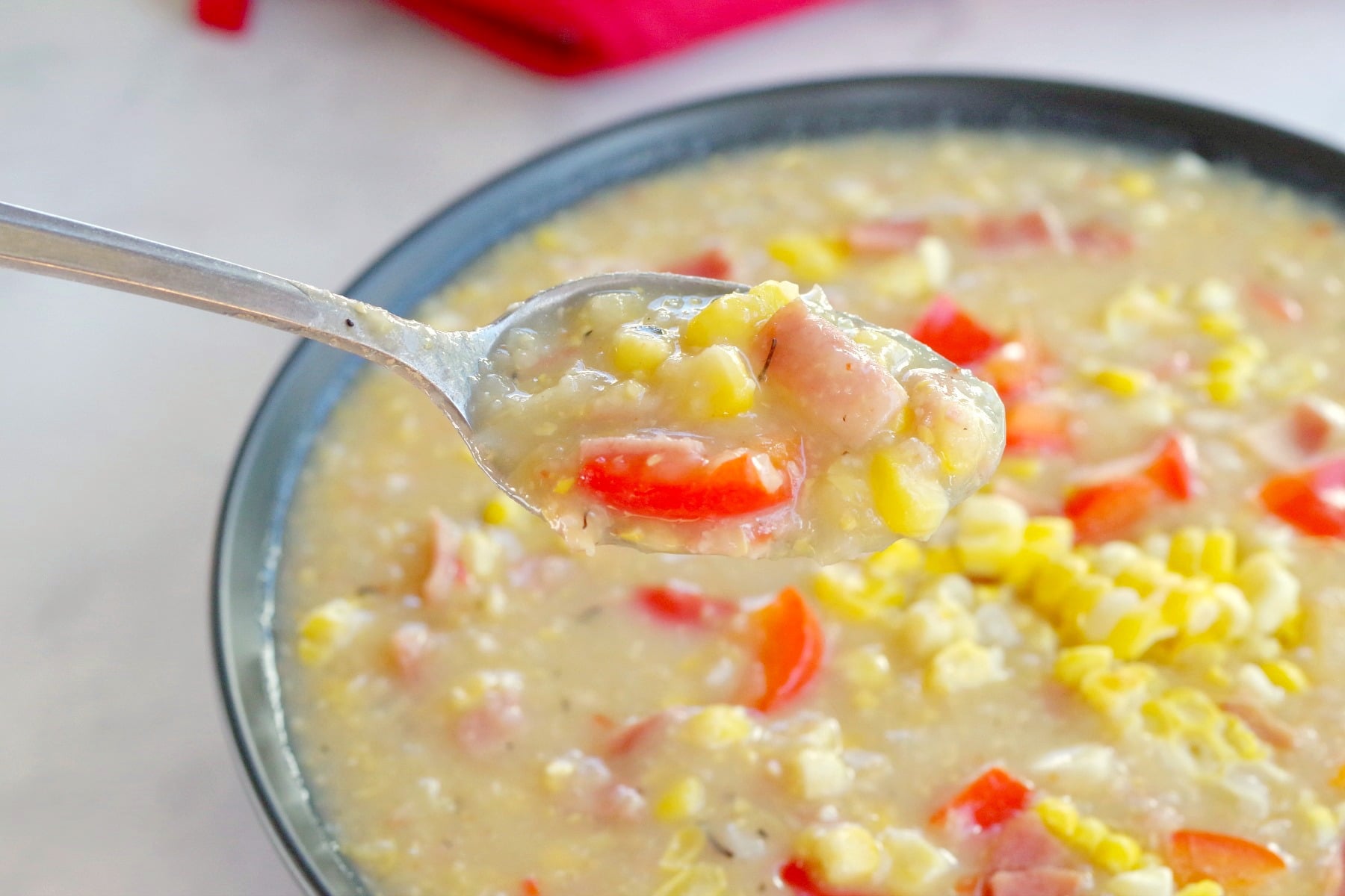 corn chowder being lifted up on spoon from bowl of soup