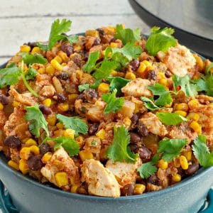 slow cooker mexican chicken in a blue dish with slow cooker in background