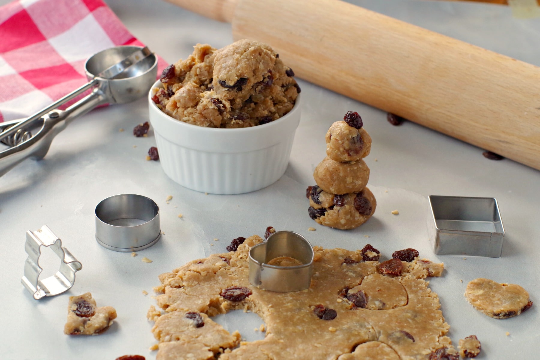 edible cookie dough rolled out and made into shapes with rolling pin in the backgroun