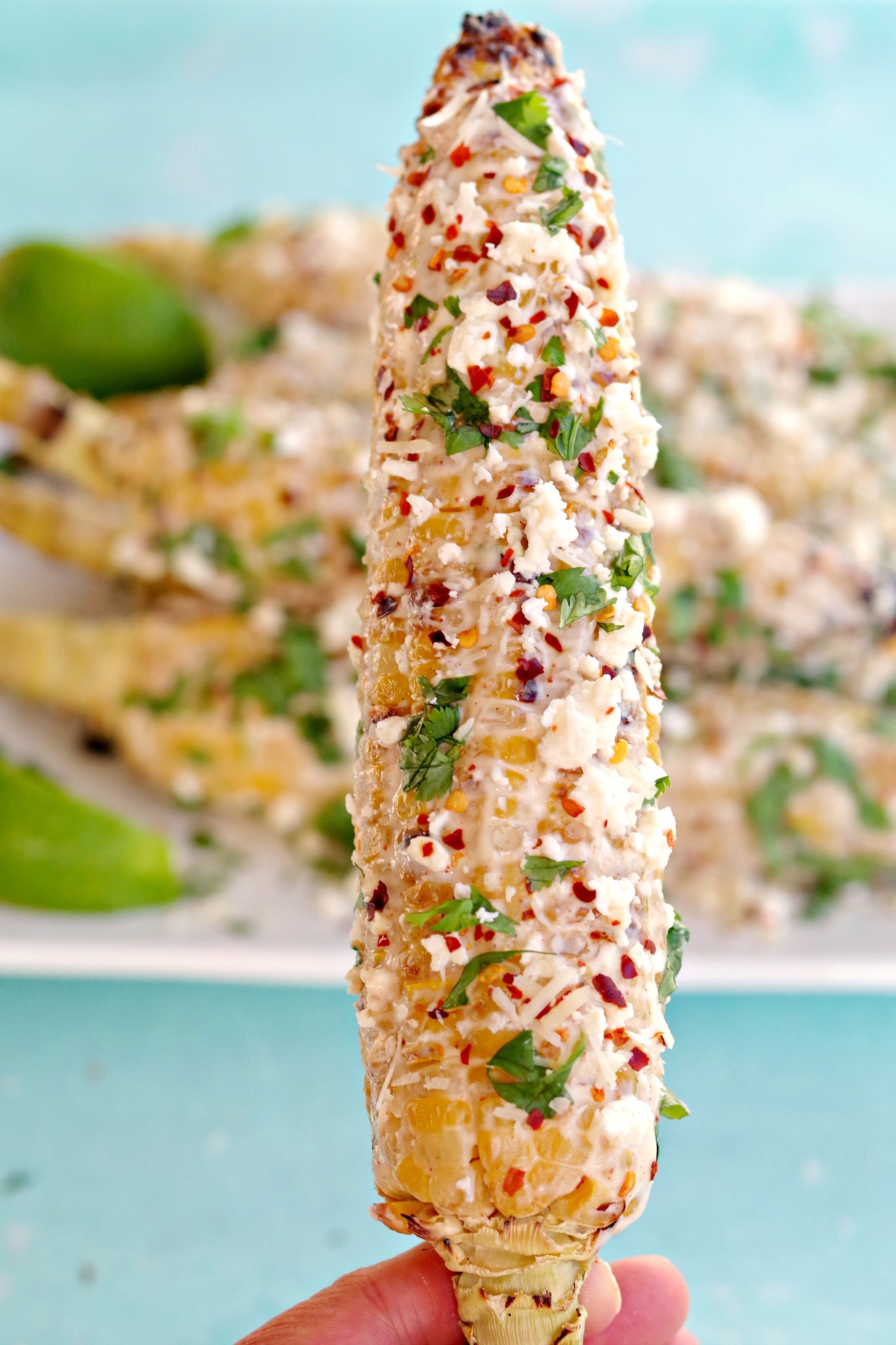 Grilled Mexican Street Corn being held up