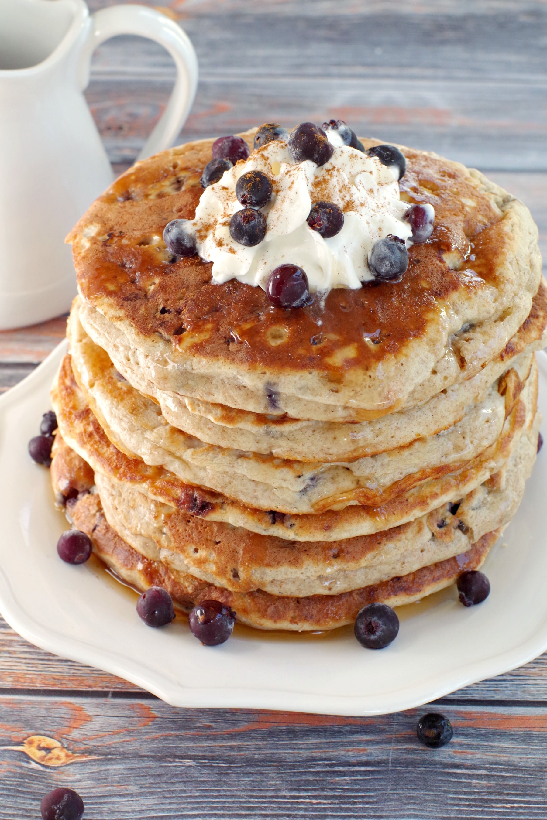 stack of Saskatoon Berry Pancakes with whipped cream and berries on top