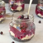 saskatoon berry cheesecake in a jar with a spoon and more jars in the background