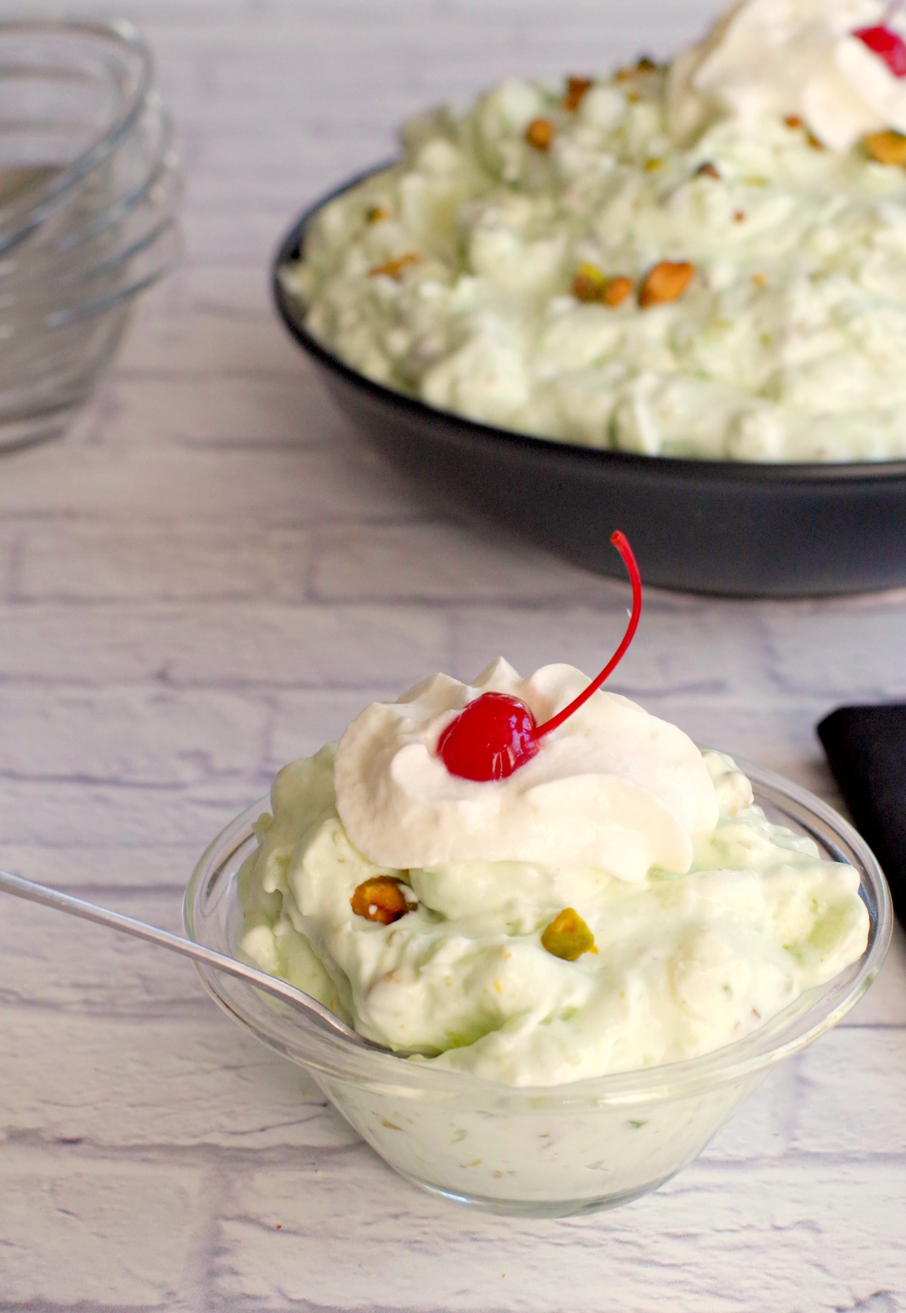 pistachio fluff in a glass bowl with a larger bowl in the background