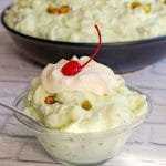 pistachio fluff in a glass bowl with a larger bowl in the background