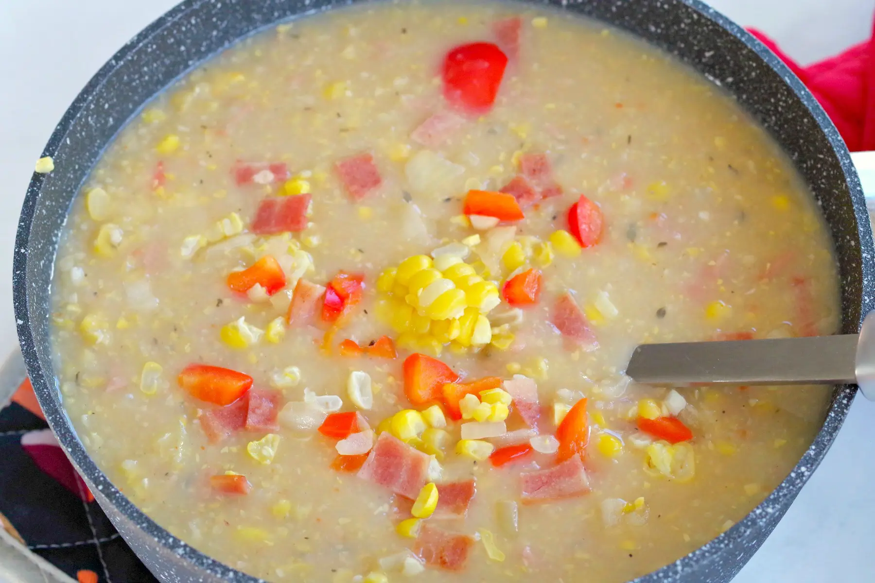 corn chowder in a pot with a ladel
