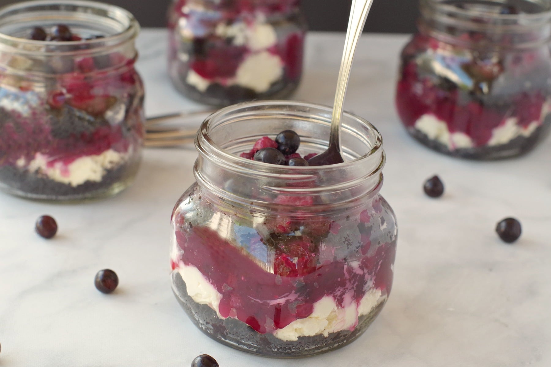 saskatoon berry cheesecake in a jar with a spoon and more jars in the background