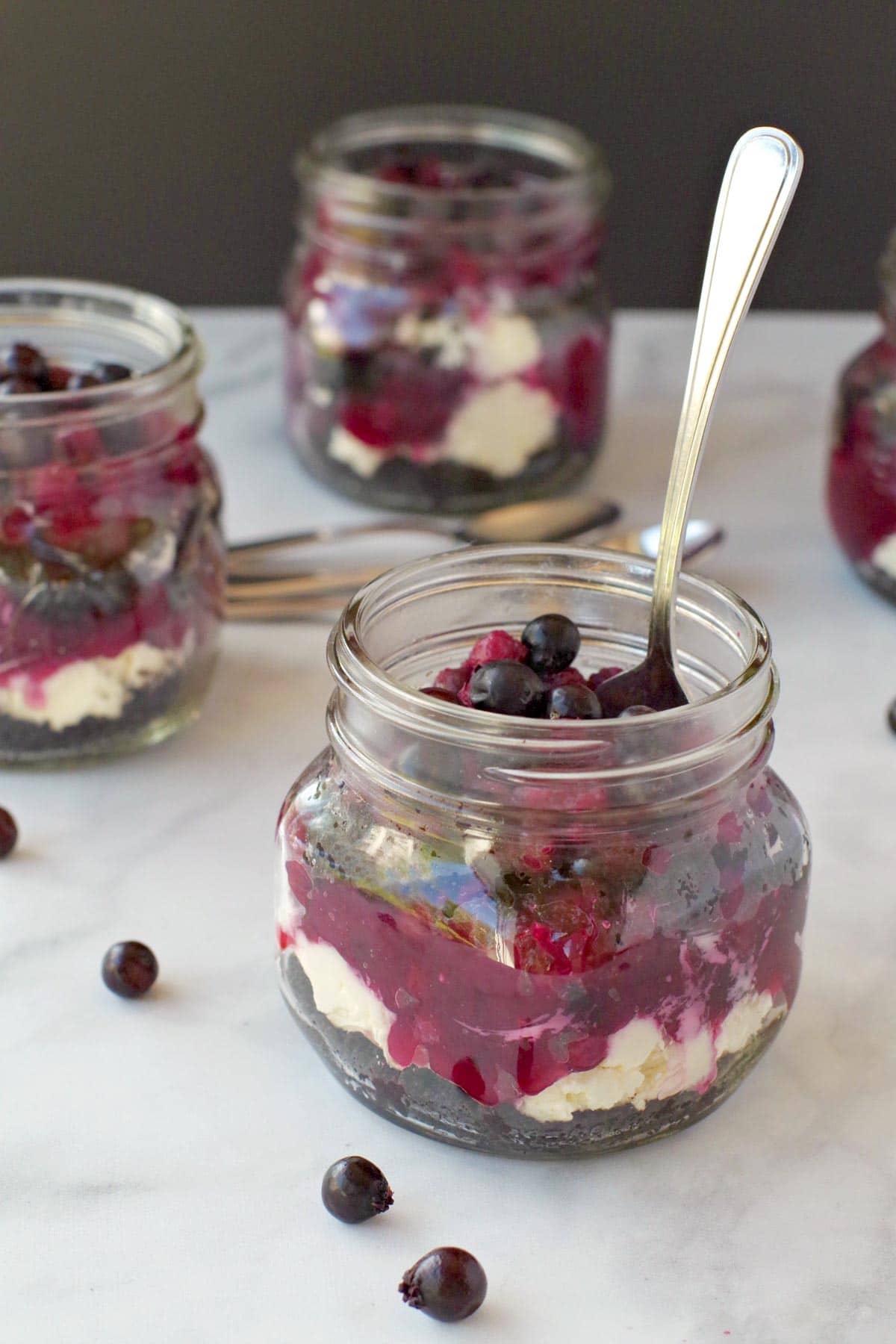 4 jars of No Bake Saskatoon berry cheesecake (one in front with spoon)