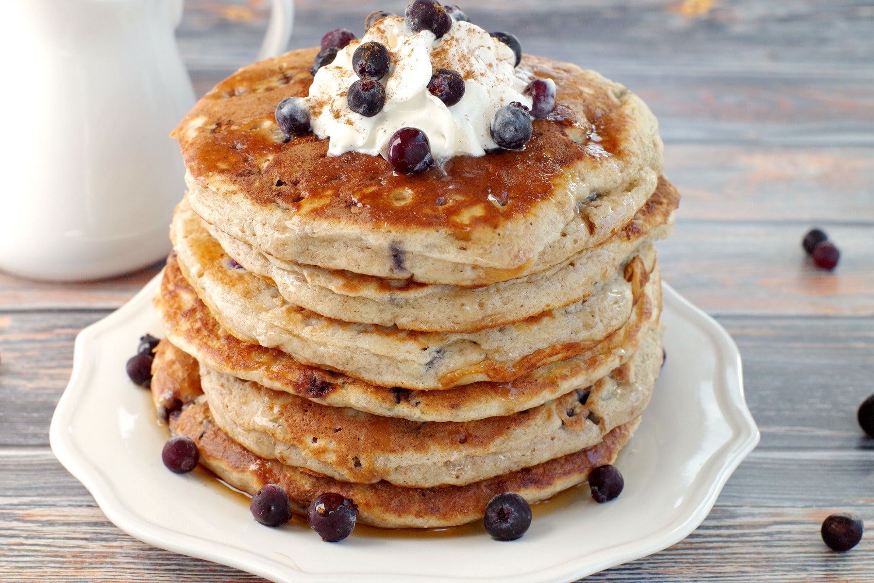 stack of Saskatoon Berry Pancakes with whipped cream and berries on top