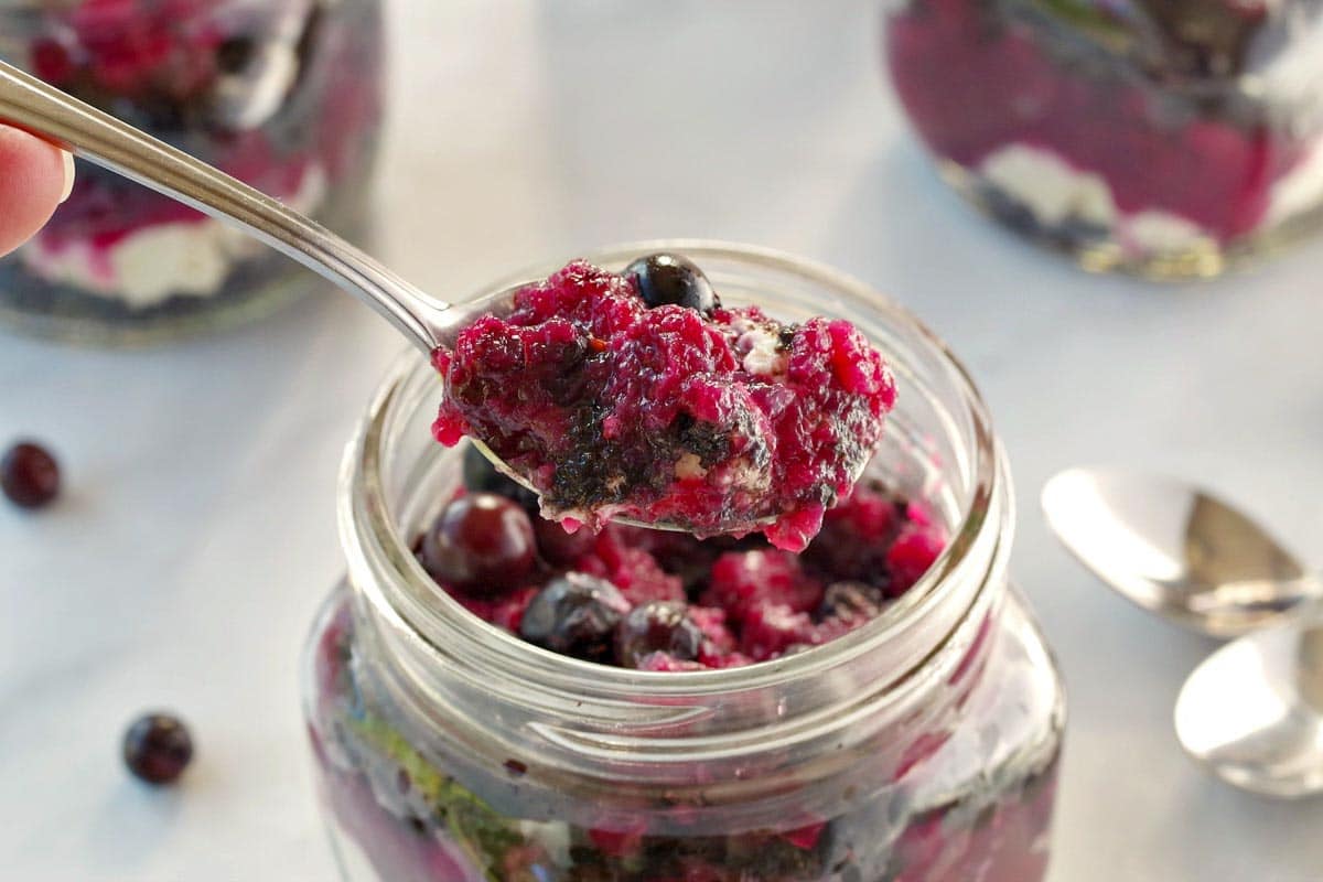 saskatoon berry cheesecake being lifted out of jar with a spoon