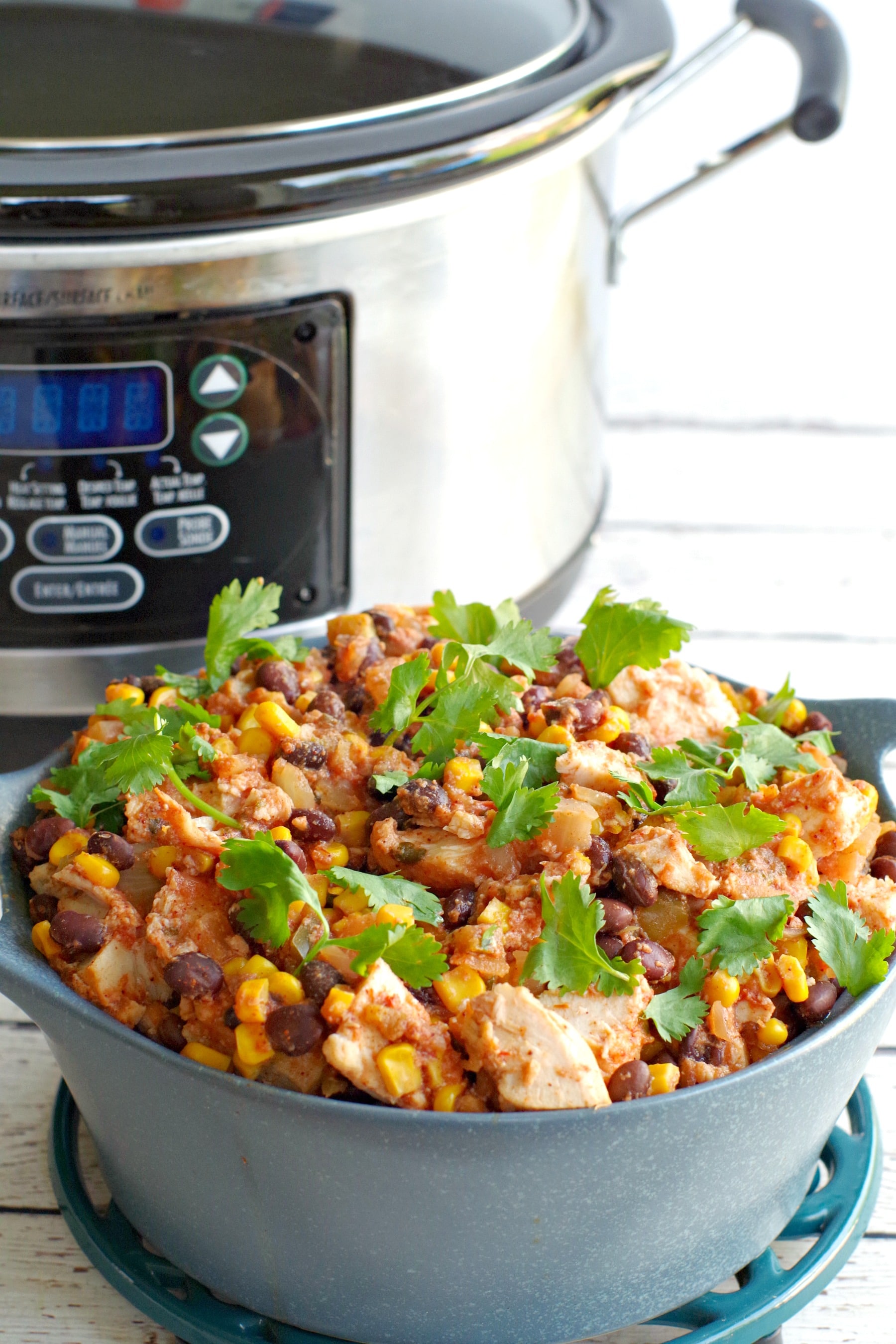slow cooker mexican chicken in a blue dish with slow cooker in background