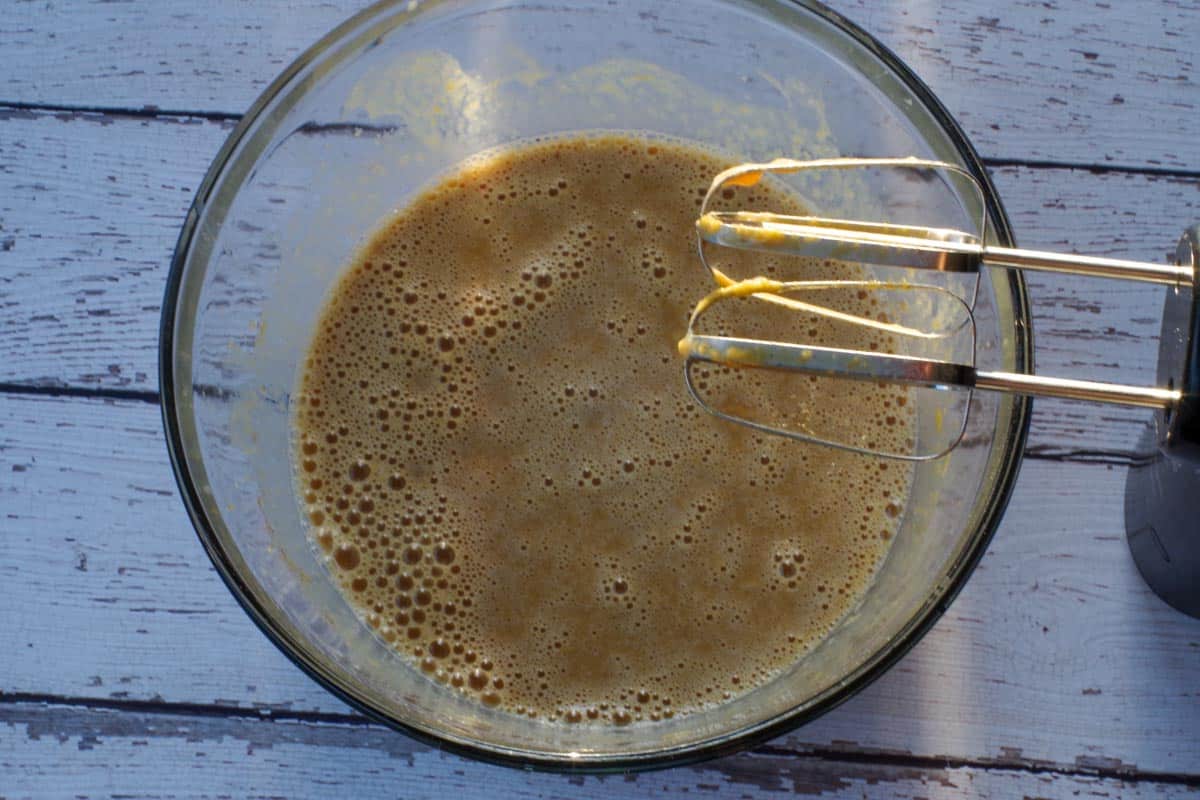 crustless pumpkin ingredients blended together in a glass bowl with beaters