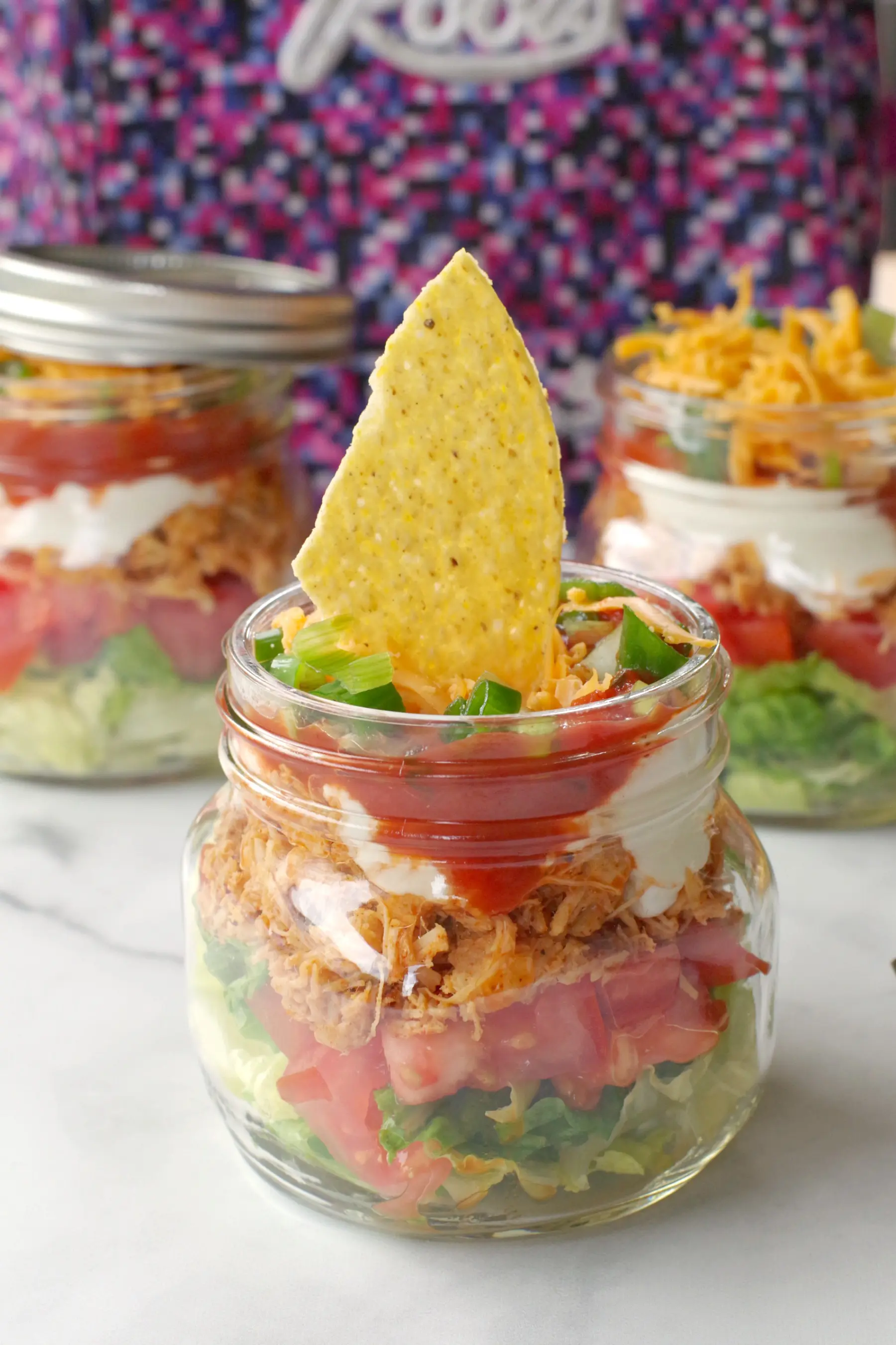 mason jar taco salad with more jars and lunchbag in background