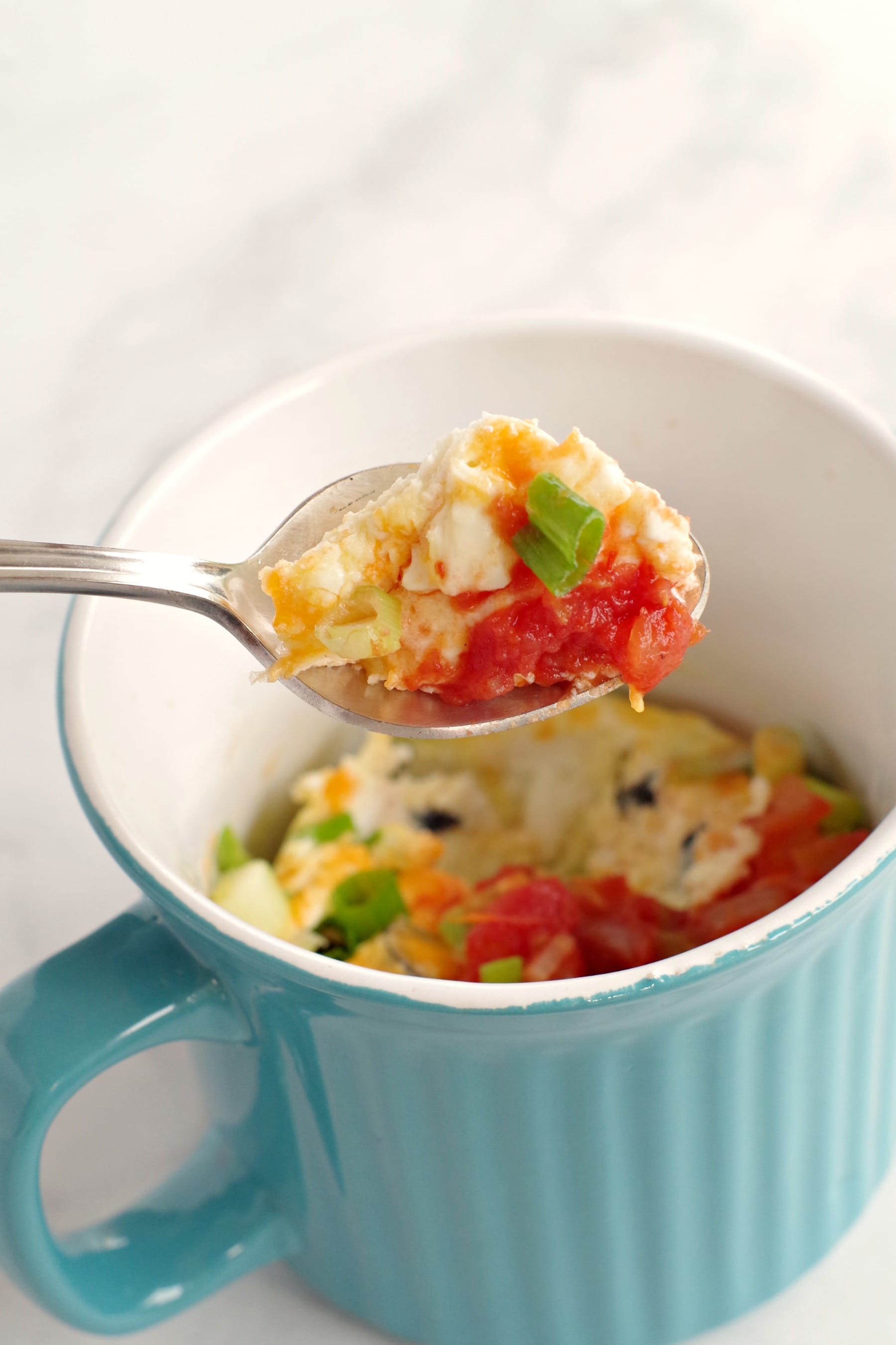 microwave mug omelette being held up on spoon over blue mug
