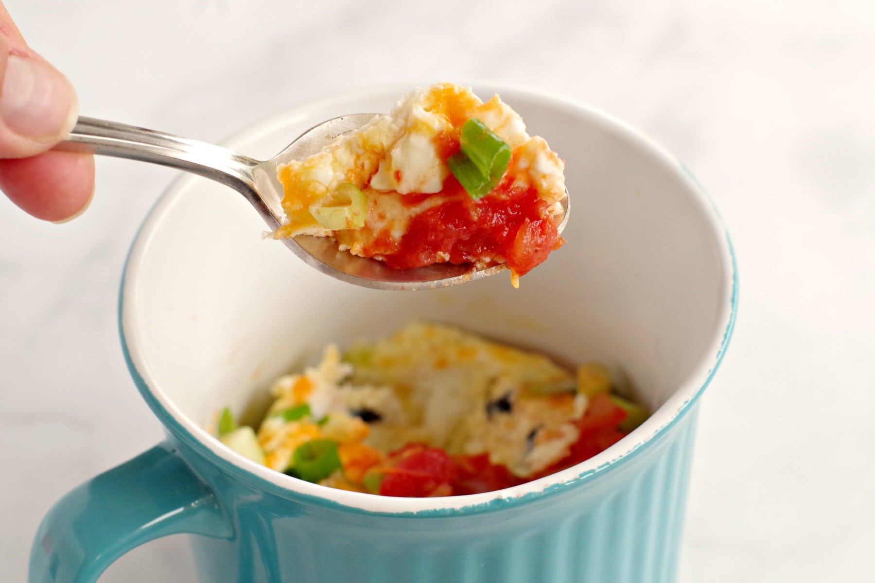 Microwave Omelette in a Mug being held up on a spoon over mug