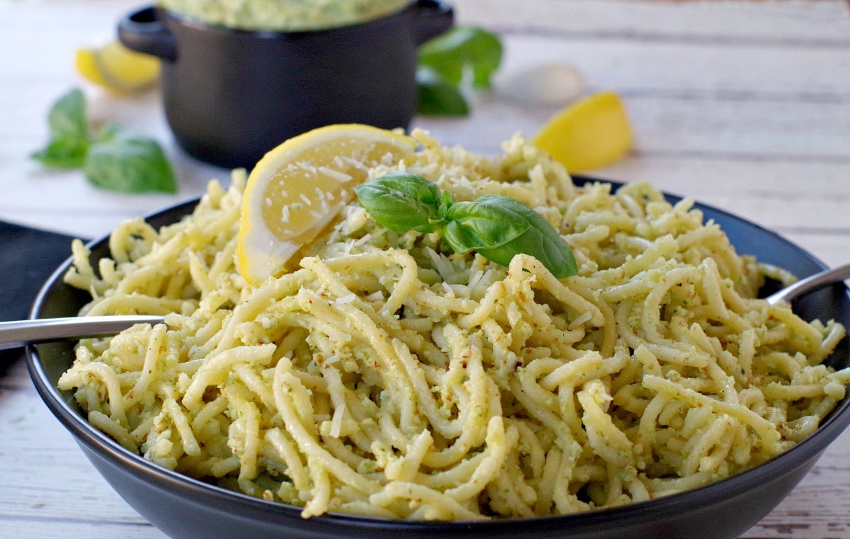 pesto on spaghetti noodles with more pesto (in black container in background)