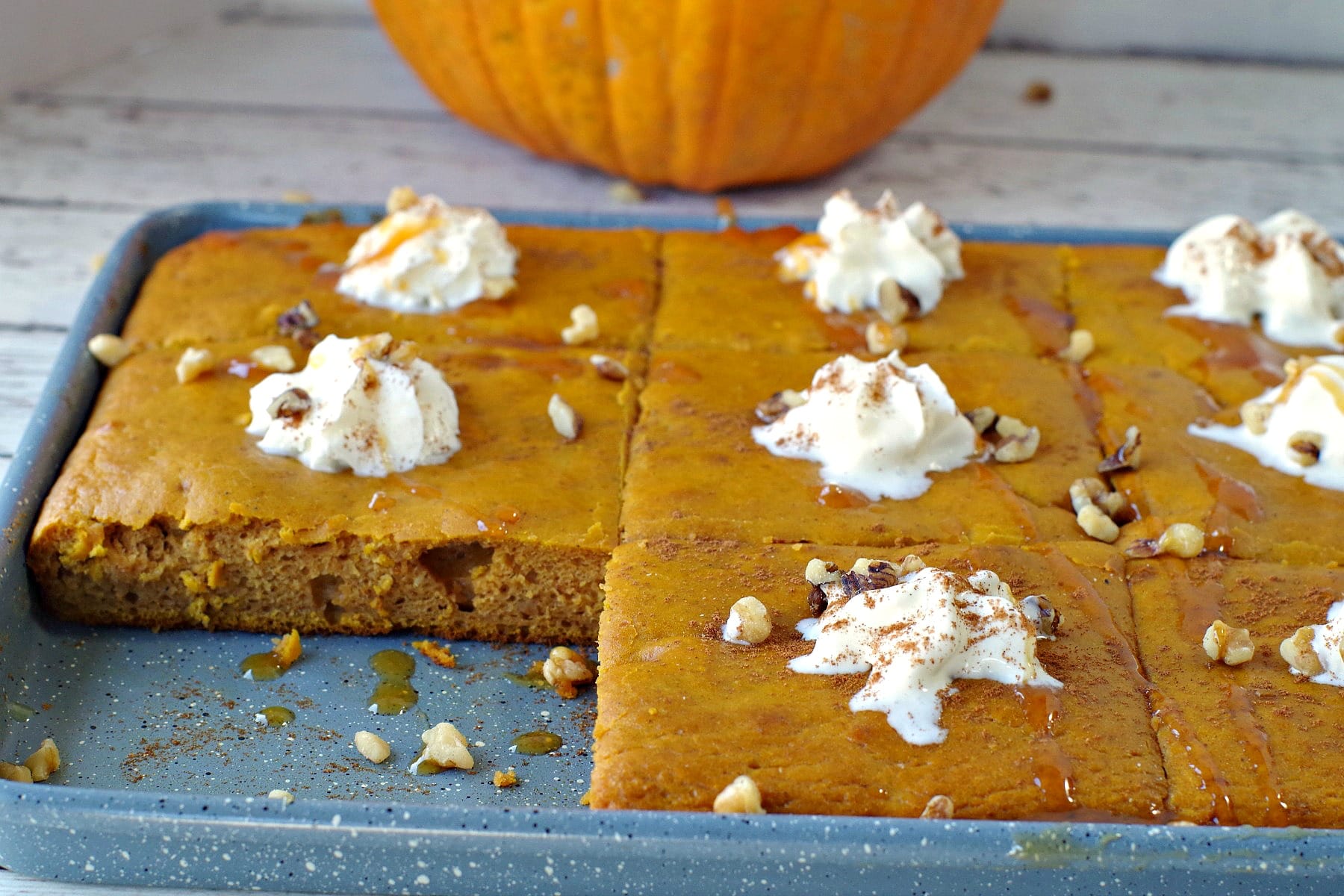 pumpkin spice pancakes on a sheet pan with one pancake missing and pumpkin in background