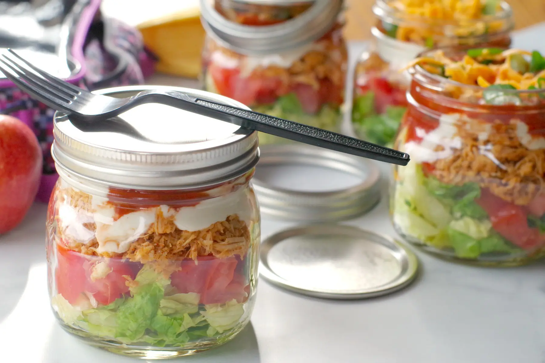 chicken taco salad in a mason jar with lid on and more jars in background