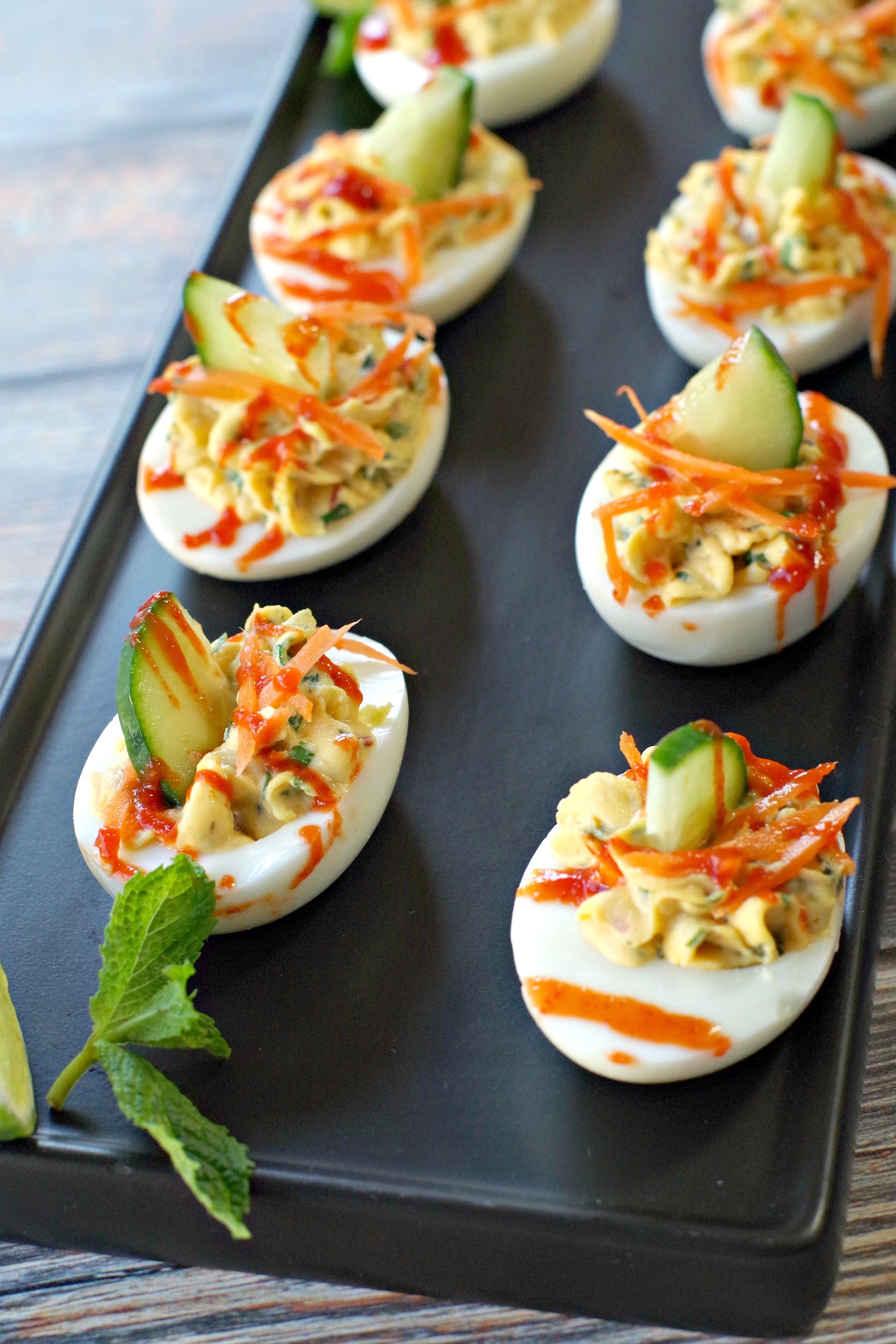 banh mi devilled eggs on a black tray with mint garnish