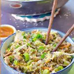 Pinterest pin with text at the top and bottom and photo of egg roll in a blue flowered bowl with chopsticks and a small white dish of plum sauce in the background and wok with more egg roll in a bowl in the background