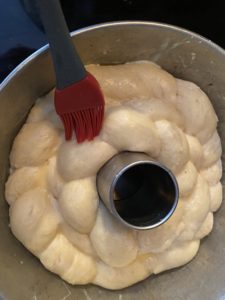 Kolach being glazed with egg wash (with red pastry brush)