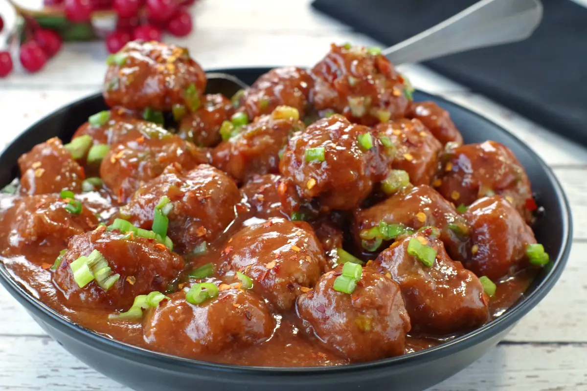 cranberry slow cooker turkey meatballs in a black bowl with a silver spoon