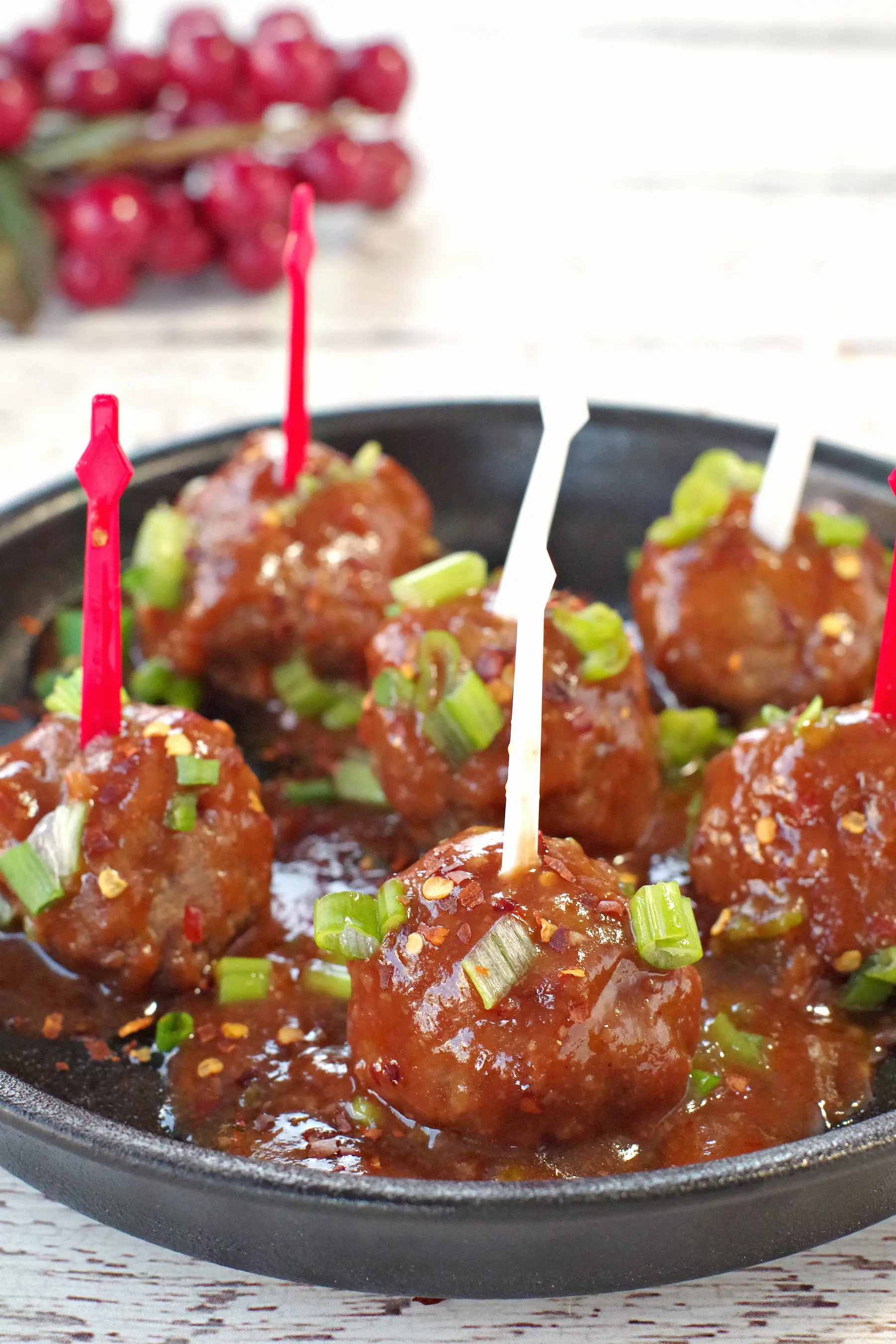 6 slow cooker turkey meatballs with red and white skewers on a black, round serving platter