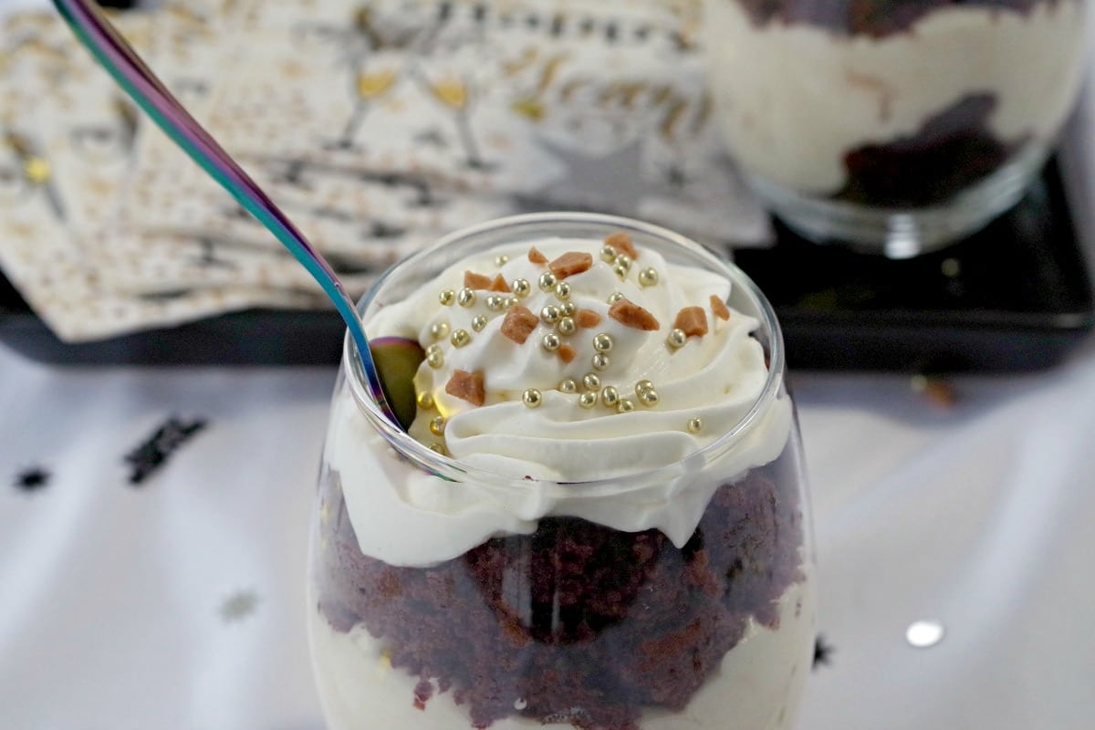 close up of top of mini eggnog trifle with spoon in it and new year's eve decorations in the background