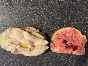 one slice of bread with fig spread, turkey, apples and brie and other other slice of bread with cranberry aioli