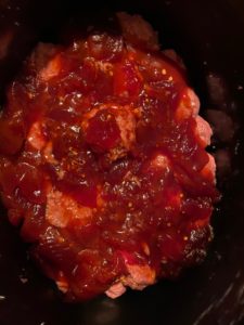 raw slow cooker turkey meatballs in the bottom of slow cooker with cranberry BBQ sauce on top