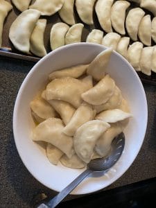 perogies added to bowl with melted butter