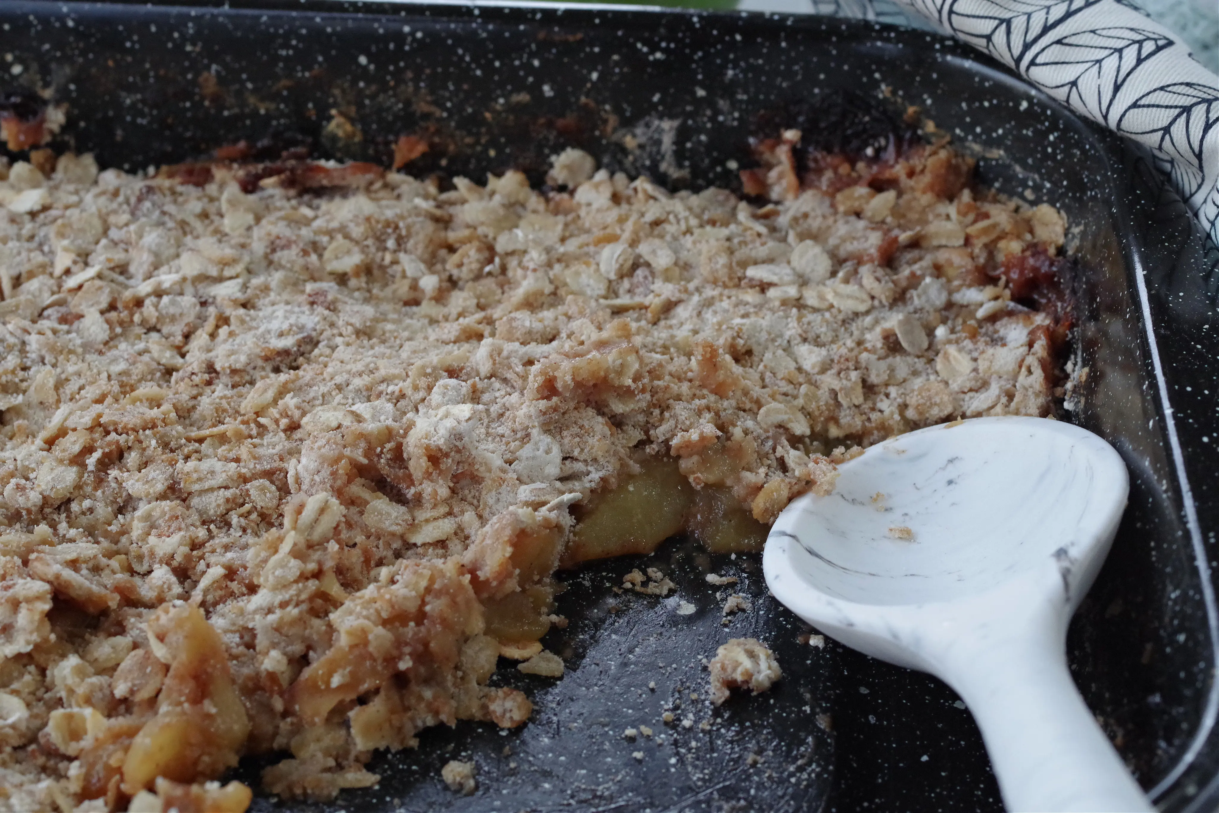pan of weight watchers apple crisp with oatmeal in a dark blue pan with a white spoon