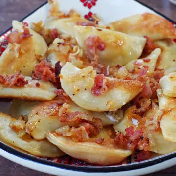 Ukrainian perogies covered in bacon and onion in a ukrainian print dish