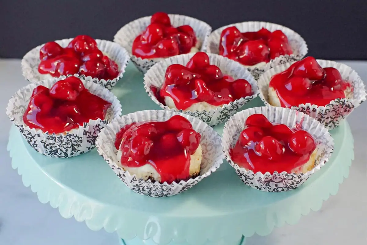 8 mini cherry cheesecakes in black and white damask print muffin liners on a light turquoise cake stand