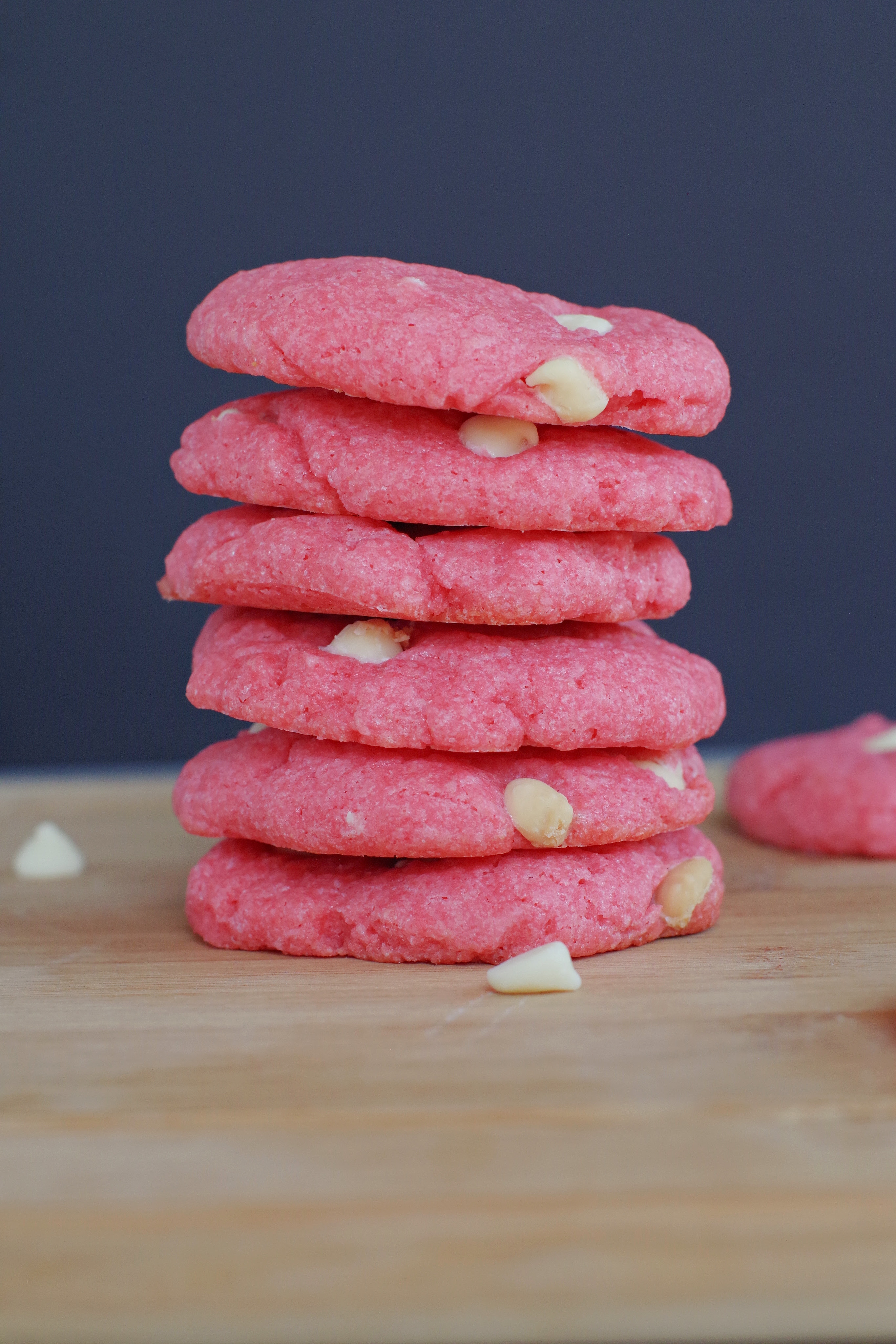 6 strawberry milkshake cookies stacked on a wood cutting board 