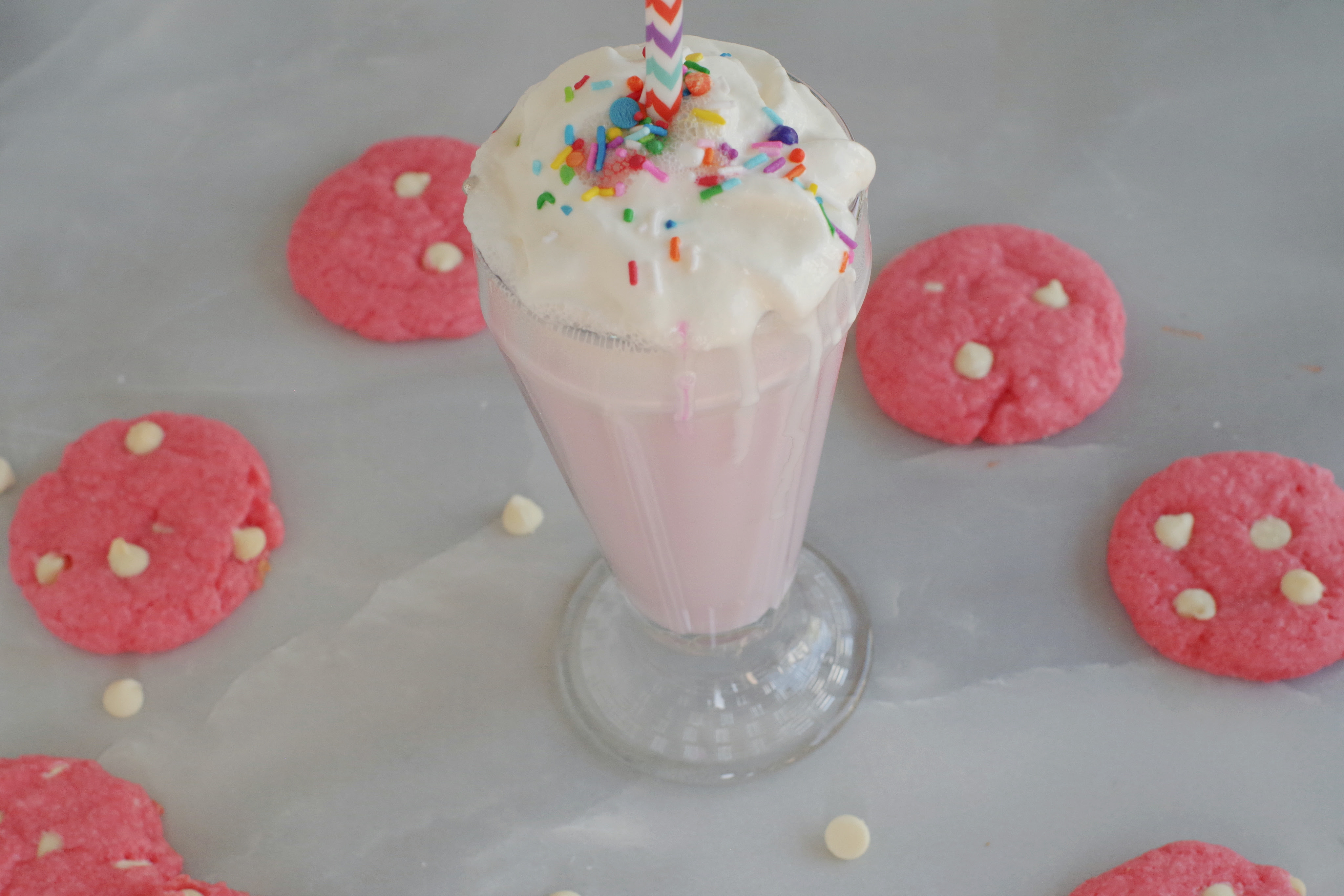 strawberry milkshake cookies in a circle around a strawberry milkshake (on grey marble background)