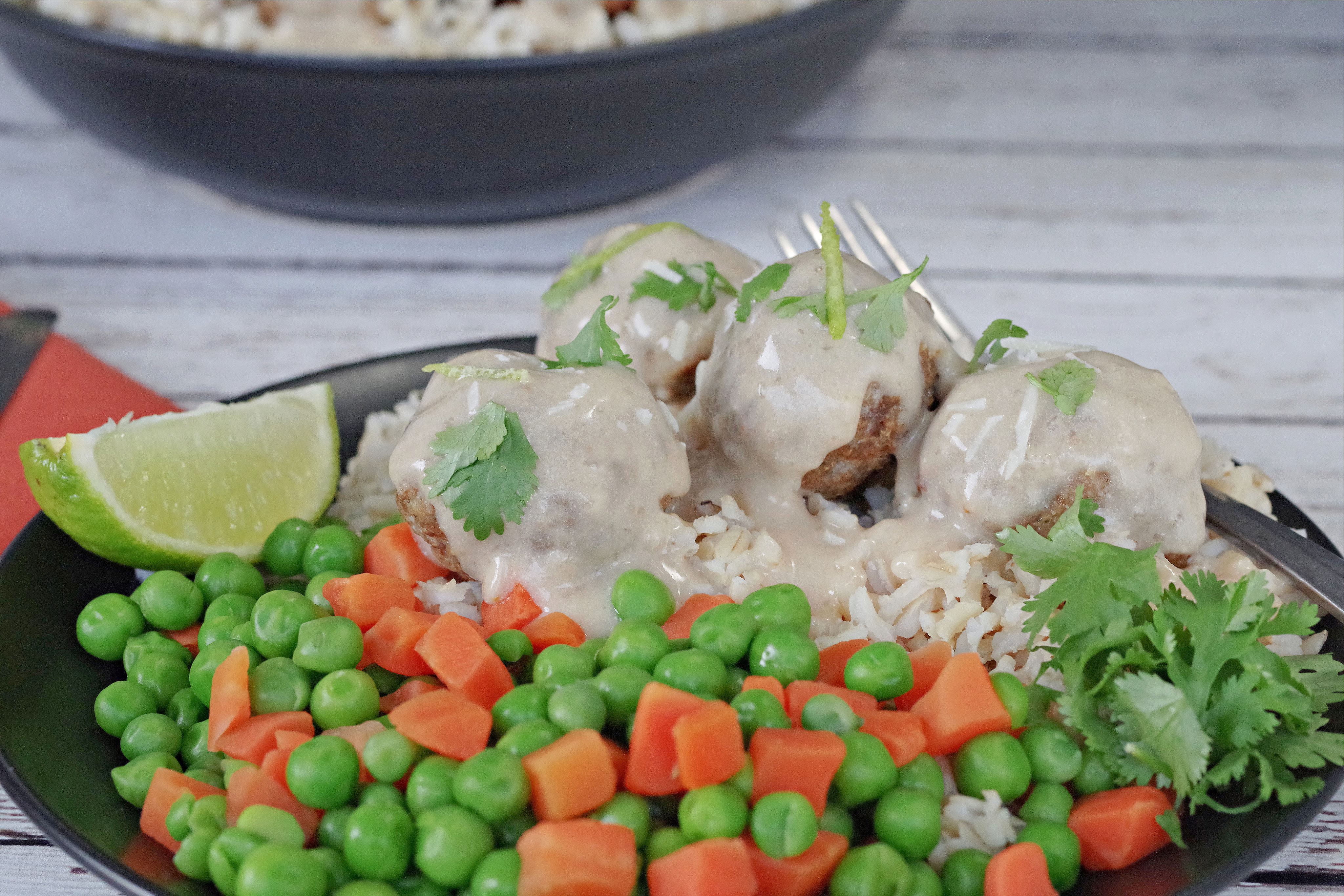 turkey pesto meatballs on rice with mixed vegetables, on a black plate