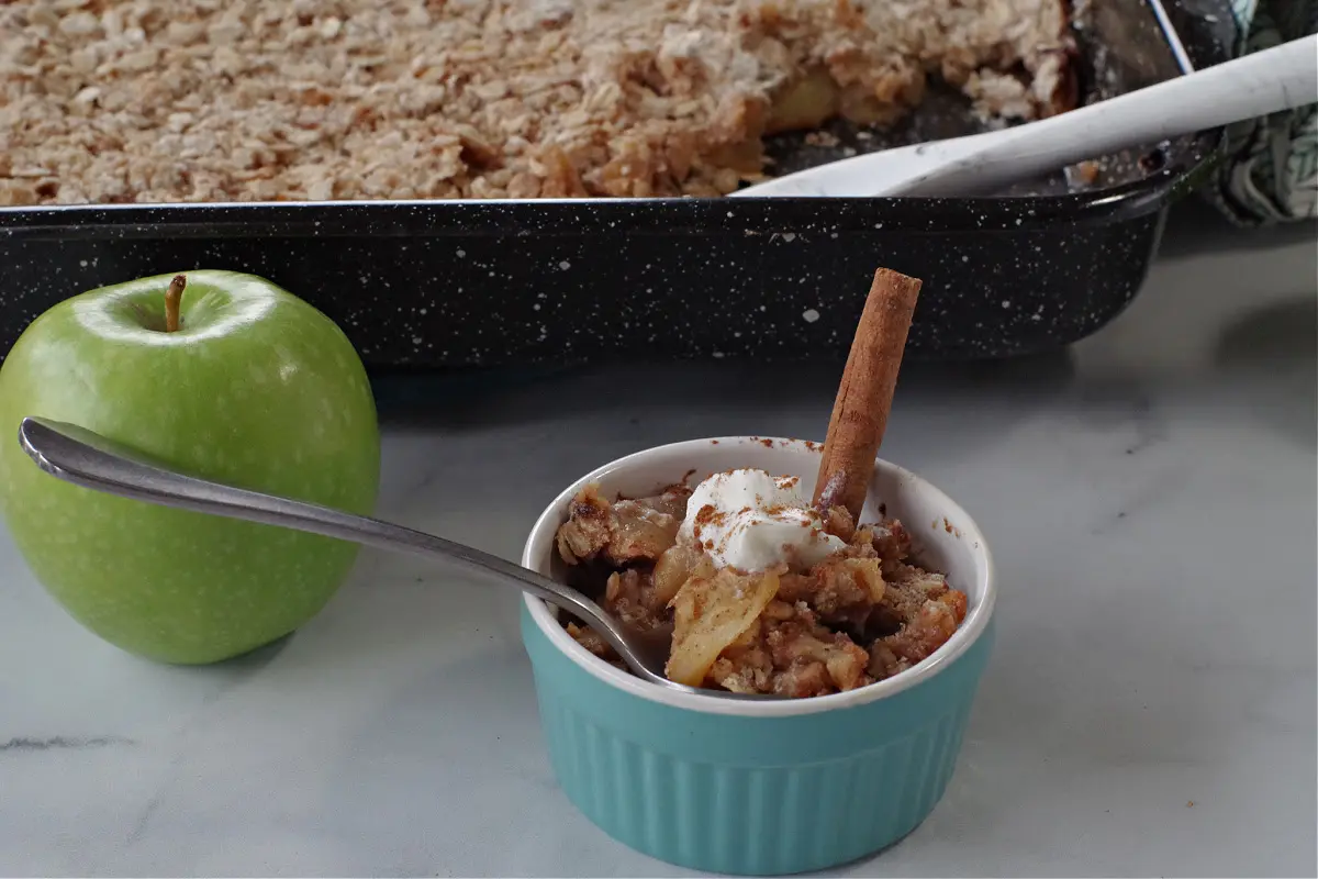 weight watchers apple crisp in a small blue bowl with a green apple and a large container in background